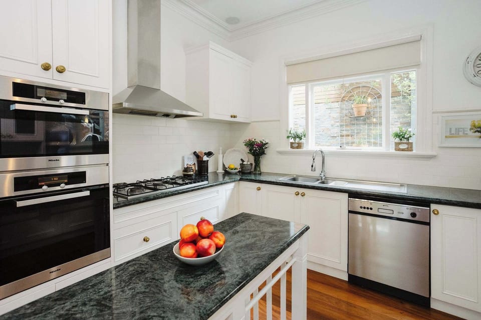 Well-equipped kitchen featuring an overhead dishwasher, a sleek cooktop, and ample counter space, designed for ease and functionality in meal preparation.