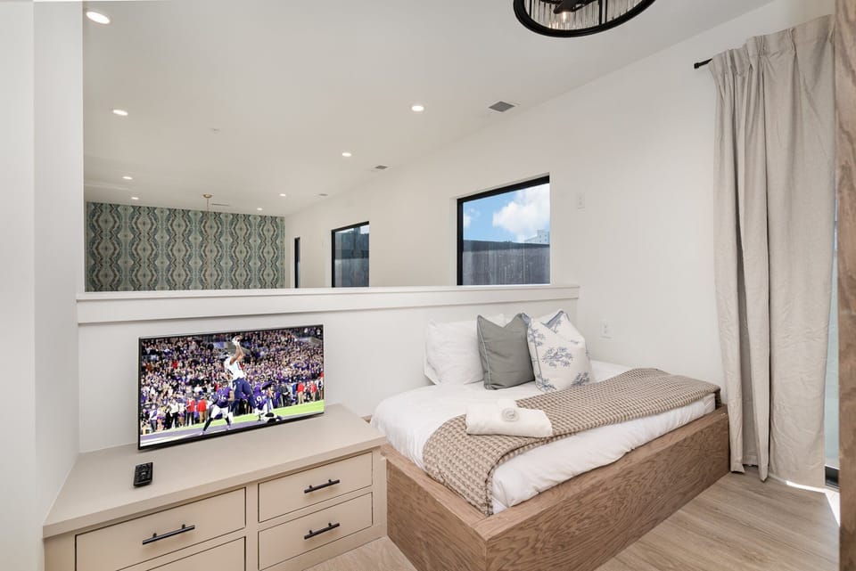 Relax in the versatile second bedroom, featuring a queen-over-queen bunk bed, a smart TV, a cozy twin bed, and private access to the top-story balcony.