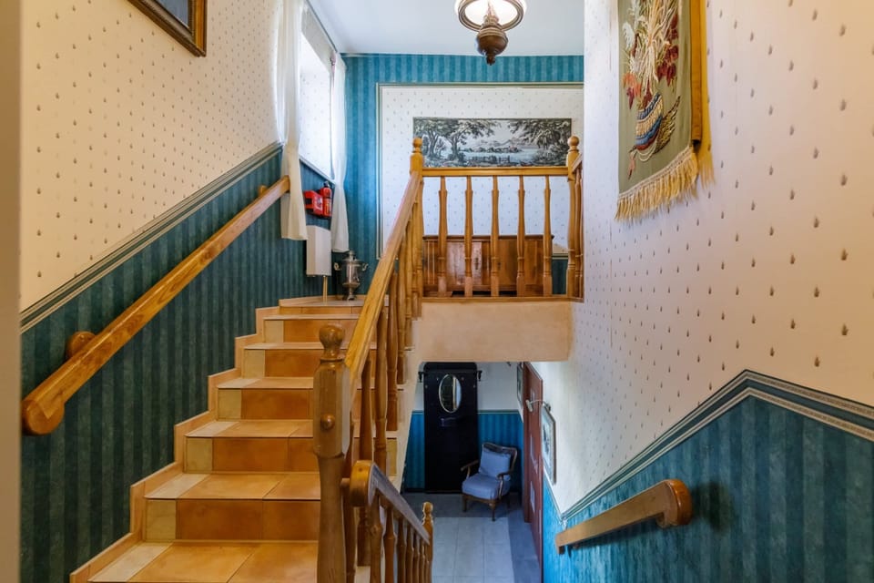A charming staircase with wooden steps and green paneling, leading to the upper floor.
