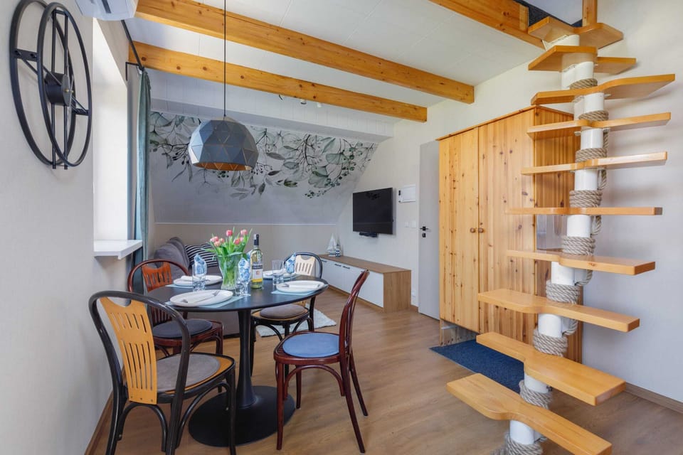 A dining area with a round table, stylish chairs, and a view of the wooden staircase.
