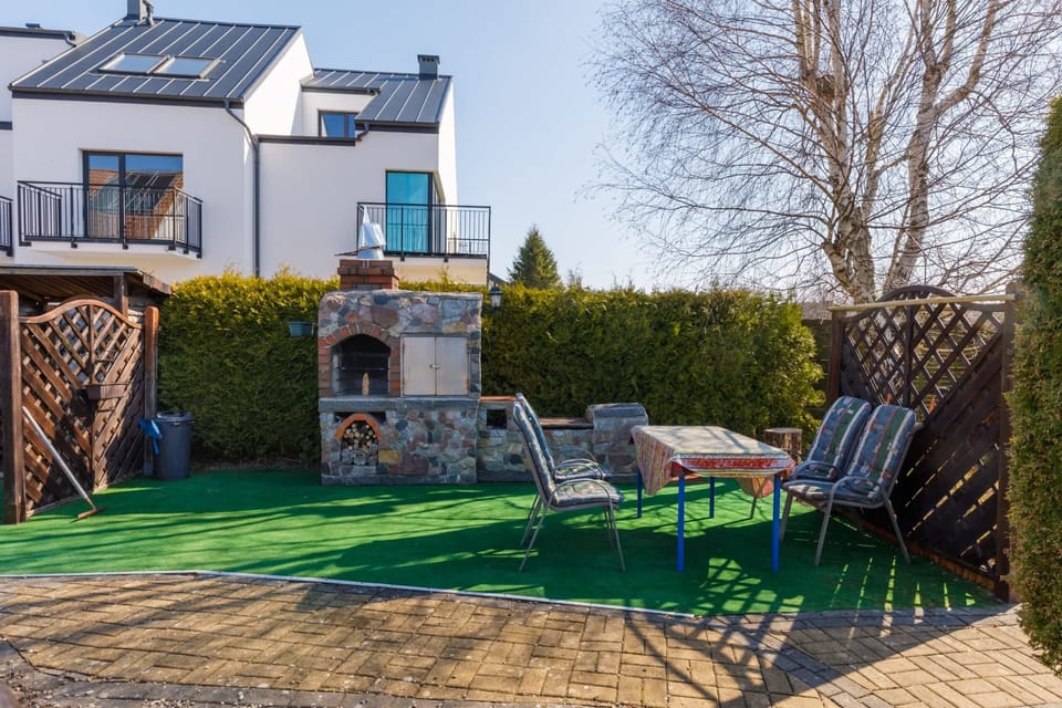 An outdoor seating area with a barbecue grill, surrounded by lush greenery for relaxation.






