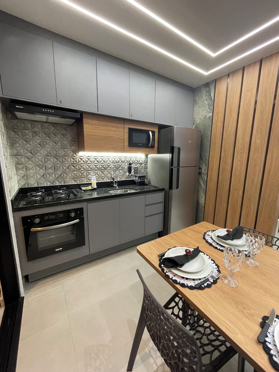 Cozinha completa com forno, cooktop, depurador, microondas e geladeira.