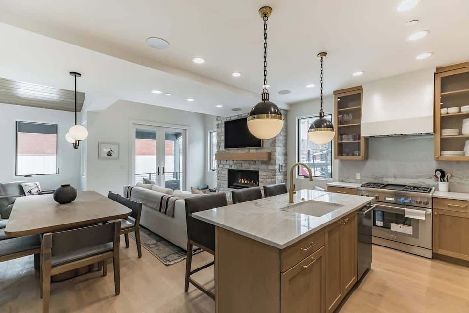 Modern open kitchen and living area with a cozy fireplace, spacious dining, and plenty of light—perfect for cooking, relaxing, and gathering.
