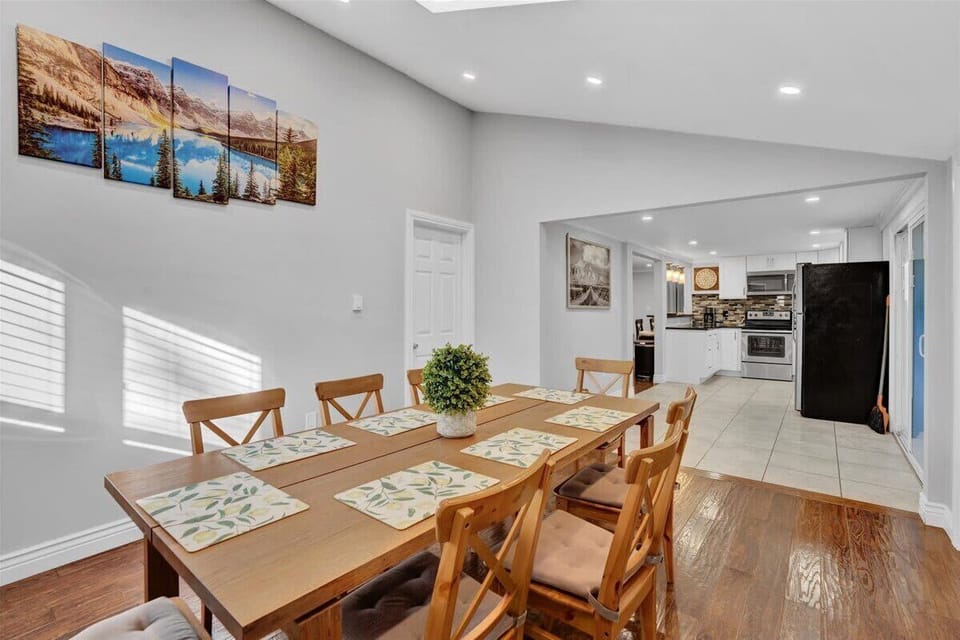 Open-concept dining and living area with wooden table, canvas wall art and hardwood floors