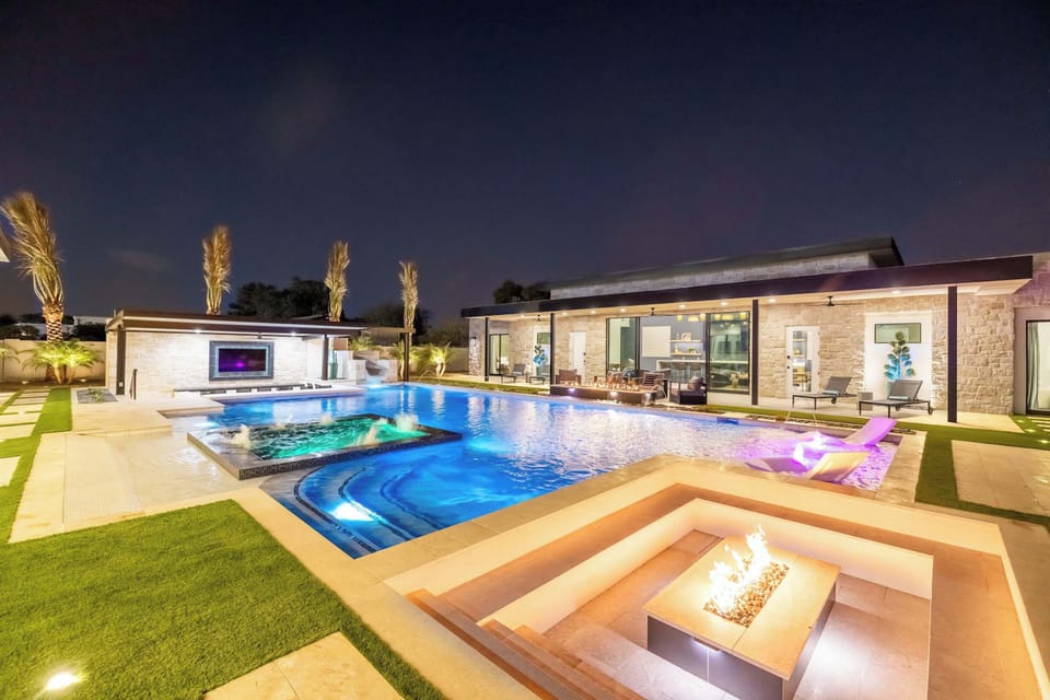 Relax by the sunken fire pit beside a glowing pool under the evening sky