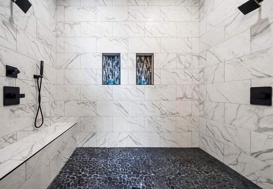 Enjoy a refreshing escape in this sleek shower, featuring striking tile designs and upscale fixtures that elevate the bathroom experience.