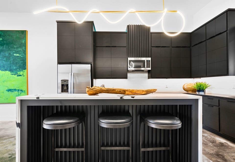 The large kitchen island is the heart of this culinary space, serving as the perfect spot for casual meals, drinks, or gathering with friends while cooking.