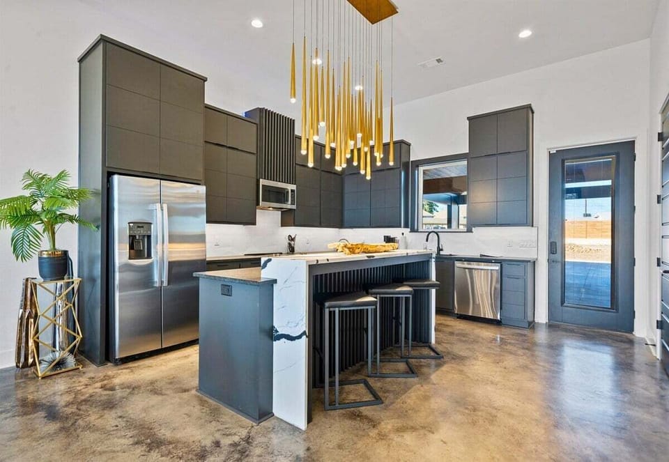 A contemporary kitchen paired with eye-catching gold lighting fixtures, blending style and practicality for a seamless cooking and entertaining experience.