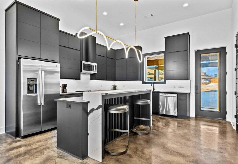This modern kitchen combines sleek cabinetry, bold gold lighting, and a spacious layout, creating a stylish hub for cooking and entertaining.