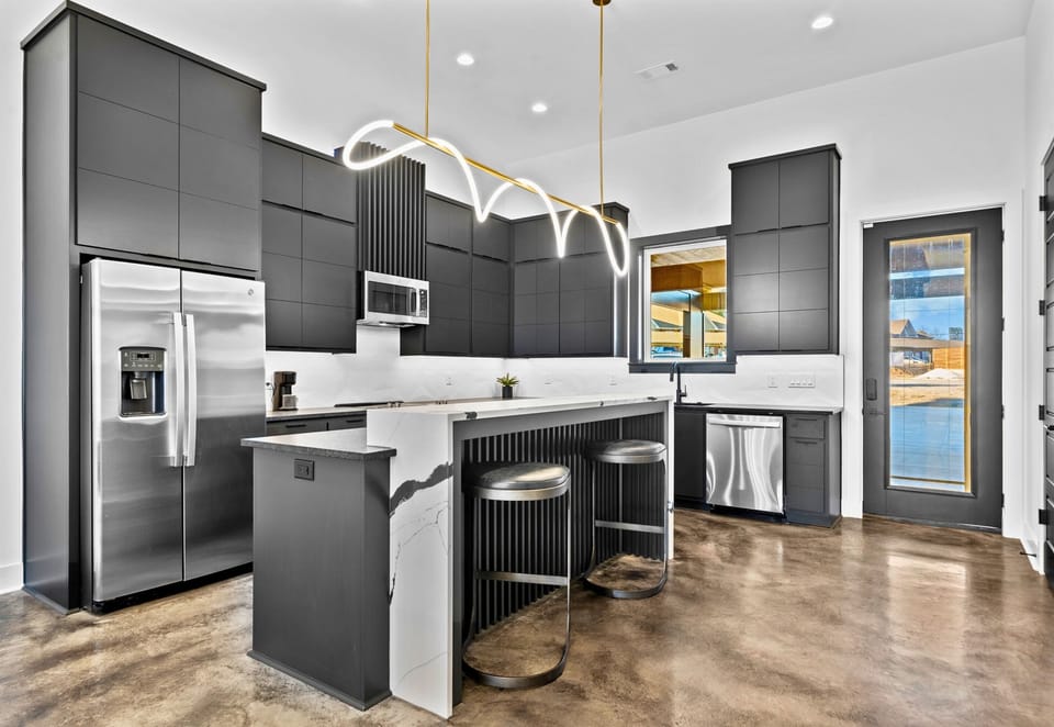 This modern kitchen combines sleek cabinetry, bold gold lighting, and a spacious layout, creating a stylish hub for cooking and entertaining.
