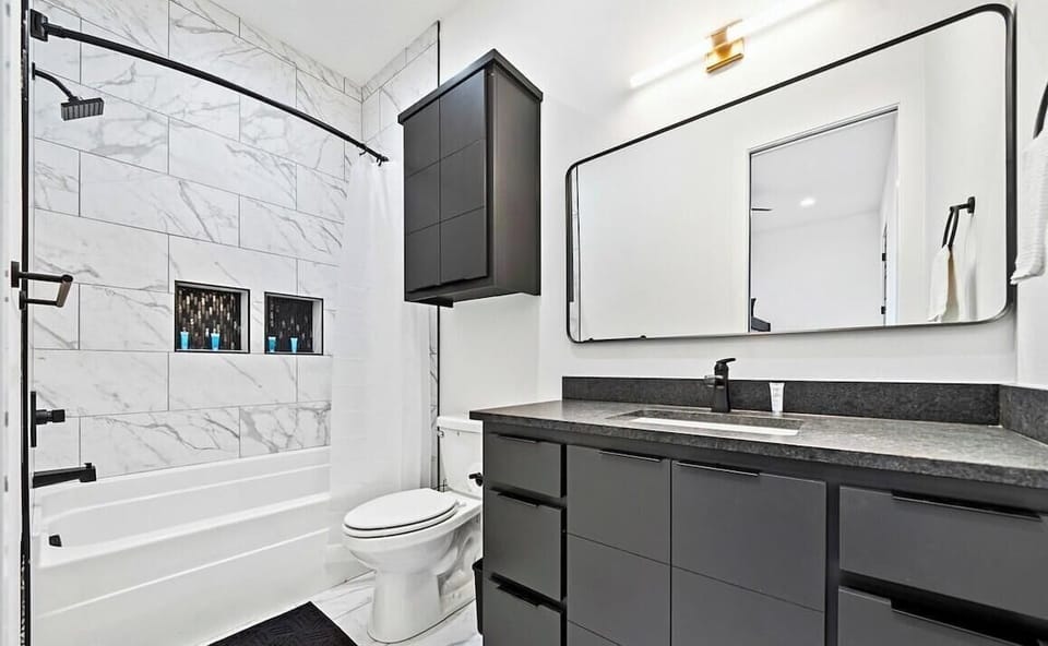 This bathroom combines sleek fixtures, a spacious vanity, and a stylish shower-tub combination for a refreshing and functional layout.