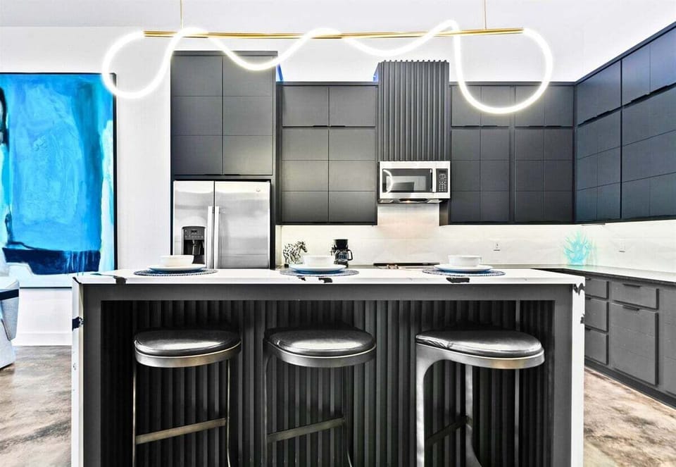 This modern kitchen impresses with clean cabinetry, striking gold accents, and a spacious island that's as functional as it is stylish.
