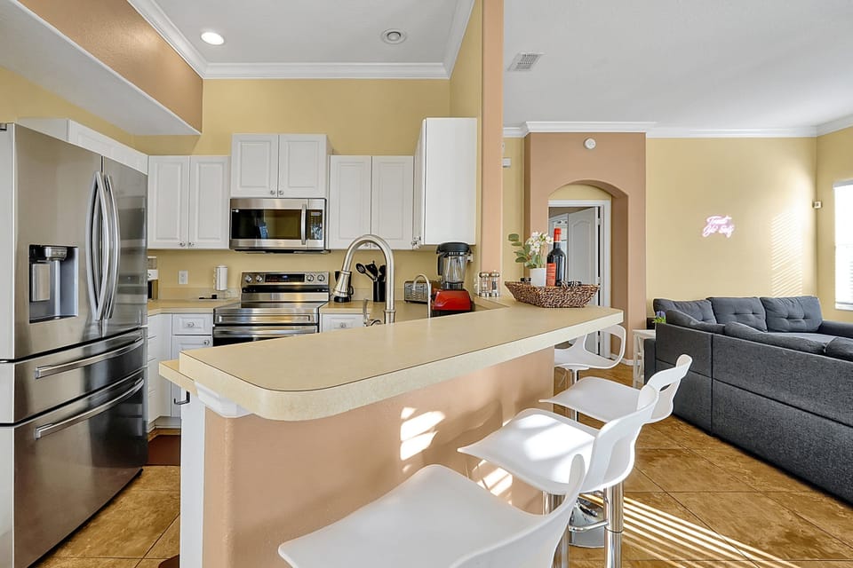Modern kitchen featuring stainless steel appliances and a breakfast bar with extra seating.