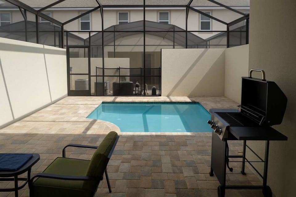Step into your private oasis, featuring a refreshing pool framed by a sleek stone patio and an inviting outdoor grill station. The screened enclosure ensures you can enjoy sunshine in a tranquil setting, perfect for relaxation.