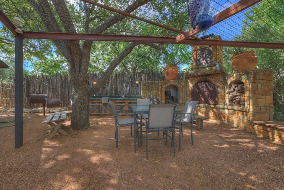 the outdoor kitchen is a dream come true, featuring a fireplace with an Argentine-style grill, a cast iron BBQ grill, and a standard gas grill.