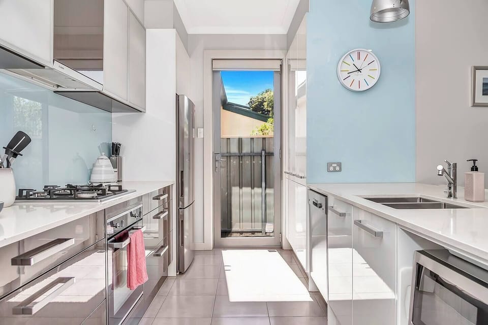 Bright and modern kitchen equipped with all cooking basics and appliances such as oven and dishwasher, ample counter space, and direct access to natural light.