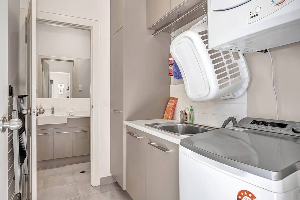 The laundry area, equipped with essentials like a washing machine and dryer, is conveniently located around the corner next to a half-bathroom.