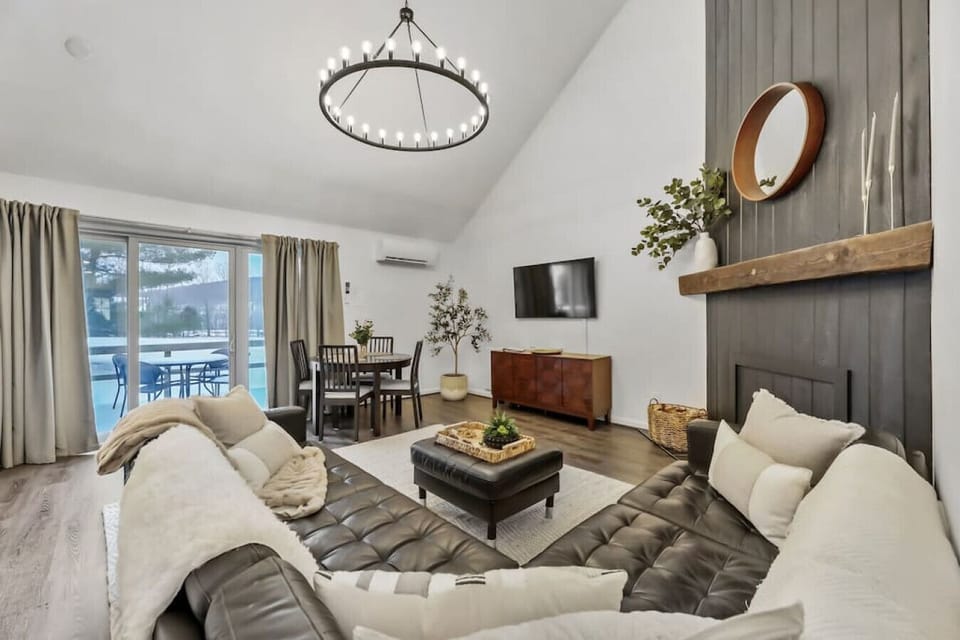Stylish and cozy living space featuring a leather sofas, chic decor, and a dining area with patio views.