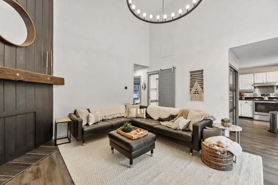Stylish and cozy living space featuring a leather sofas, chic decor, and a dining area with patio views.