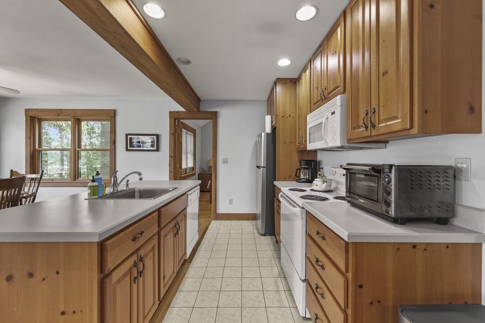 Open kitchen and dining area with large windows, wood cabinetry, and a central island.