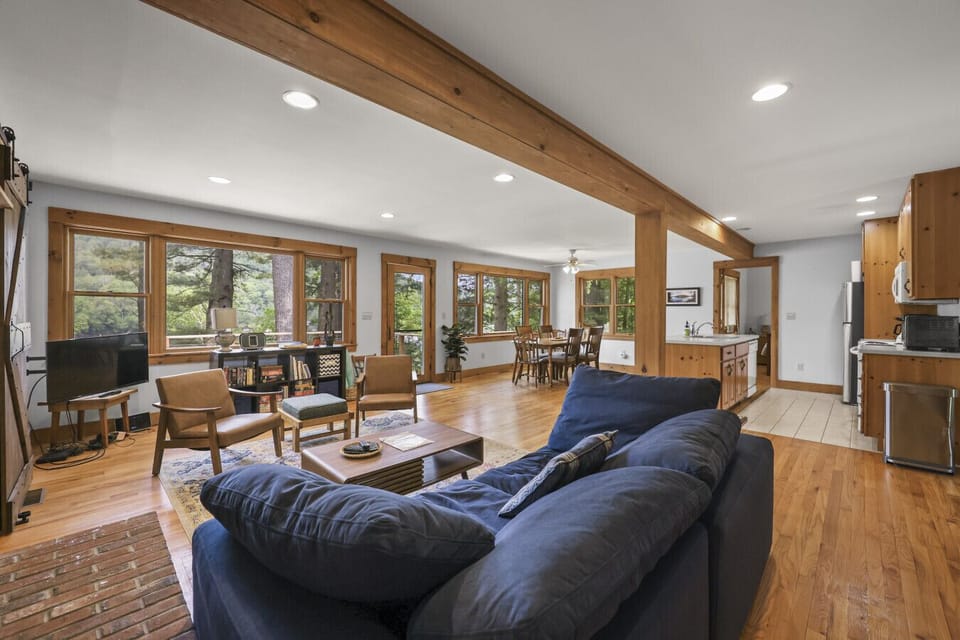 Open-concept living room with multiple sofas, TV, and wraparound windows offering scenic views.