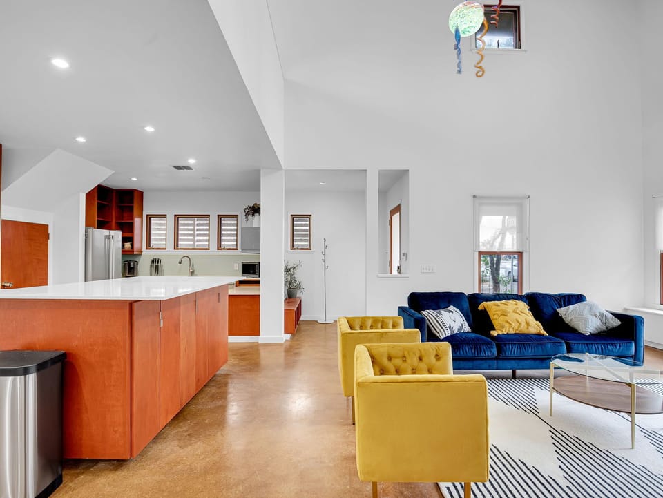 Open living room and kitchen; living room boasts a shuffle board table behind couch.