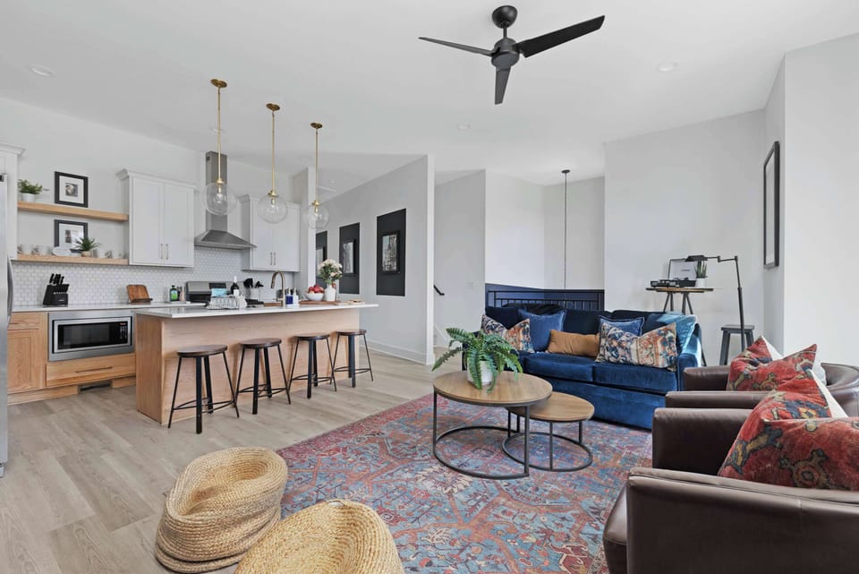 Inviting living room with a wall-mounted smart TV, a pull-out sofa bed, a stylish coffee table, and comfortable accent chairs, perfect for relaxing and entertaining.