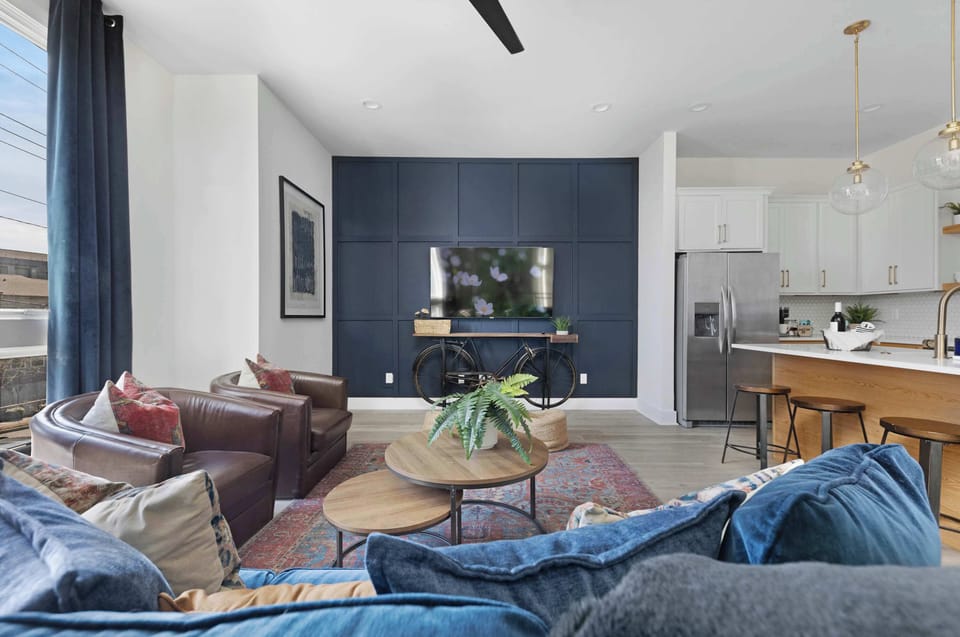 Inviting living room with a wall-mounted smart TV, a pull-out sofa bed, a stylish coffee table, and comfortable accent chairs, perfect for relaxing and entertaining.