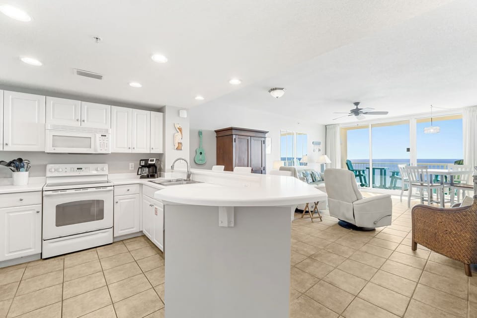 Open kitchen with white cabinetry and ocean views from the living area