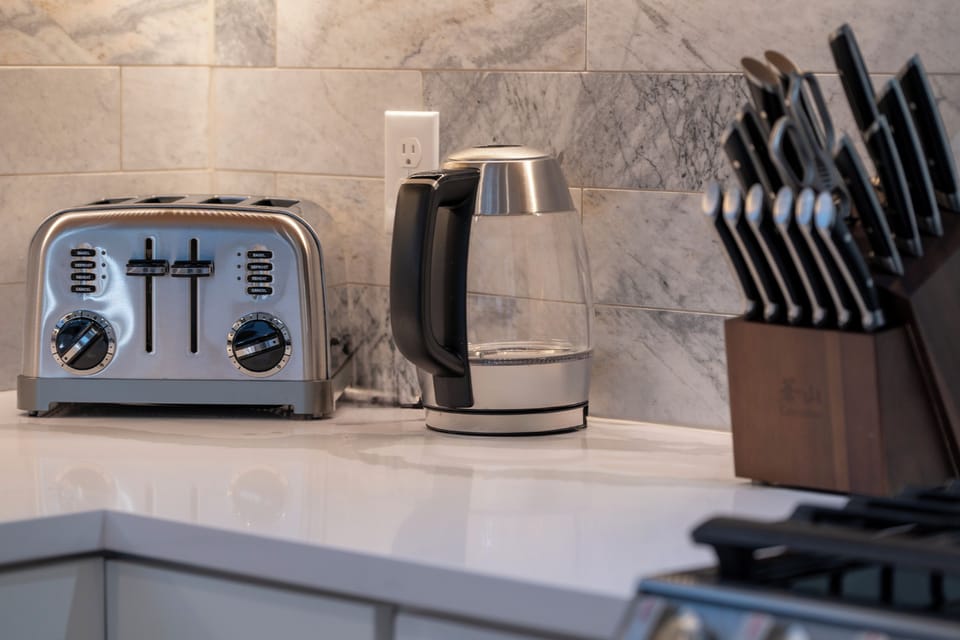 - Stainless steel toaster, glass electric kettle, and full knife set ready for your meals - Marble backsplash and sleek countertops highlight the kitchen’s clean design - Conveniently located for quick breakfast prep, coffee, or casual snacking