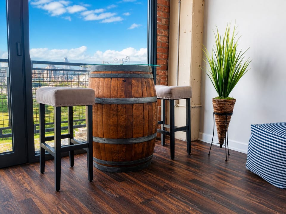 A unique and rustic bar table crafted from a barrel, paired with upholstered stools. Situated by the floor-to-ceiling windows, offering scenic views and a cozy spot for drinks or conversation.

