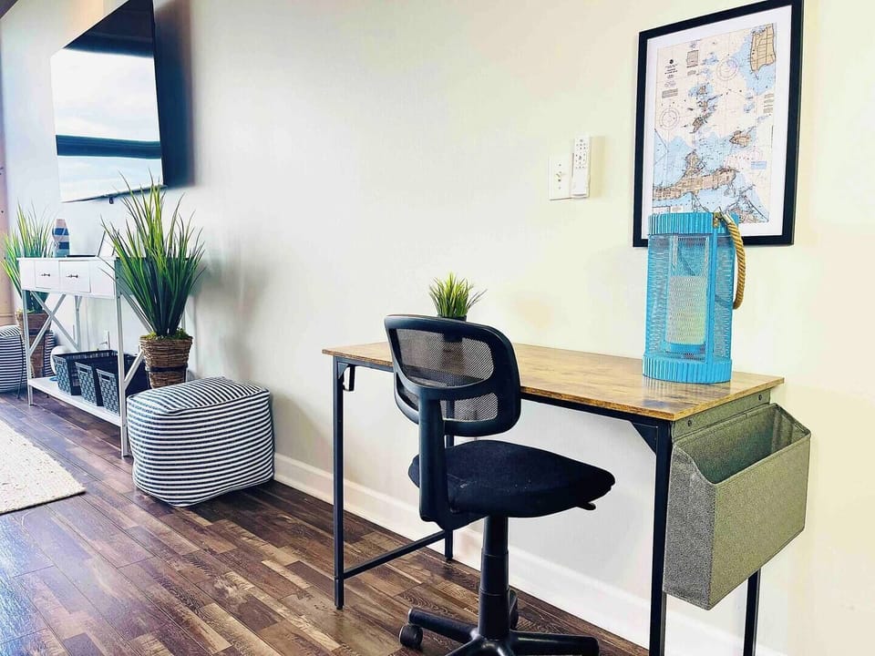  A stylish desk setup with a modern chair, perfect for remote work or journaling. Accented by a maritime-themed wall map and sleek lighting, ideal for productivity in a serene environment.

