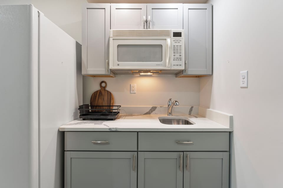 compact kitchenette with modern cabinetry, microwave and sink, for light meals