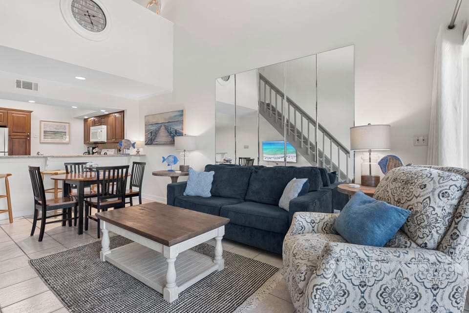 Your open-concept living space features coastal blues and comfortable seating, perfect for gathering with family after beach days.