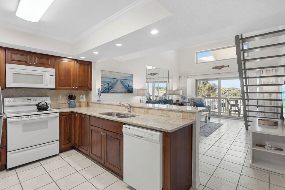 Your spacious kitchen boasts granite counters, rich wood cabinets, and modern appliances perfect for preparing coastal meals together.