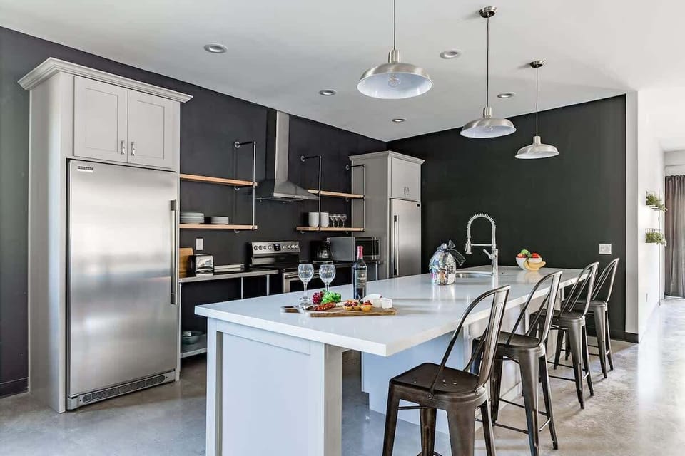 Unit 1: Fully equipped modern kitchen featuring stainless steel appliances, kitchen island with bar seating for 4 guests and a formal dining table with seating for 8 guests.