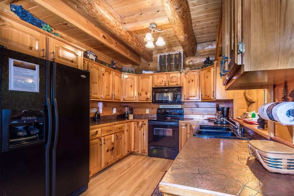 Love the blend of warm wood paneling and modern black appliances in this fully equipped kitchen! It’s the perfect space for cooking up memories. What’s your favorite dish to make?