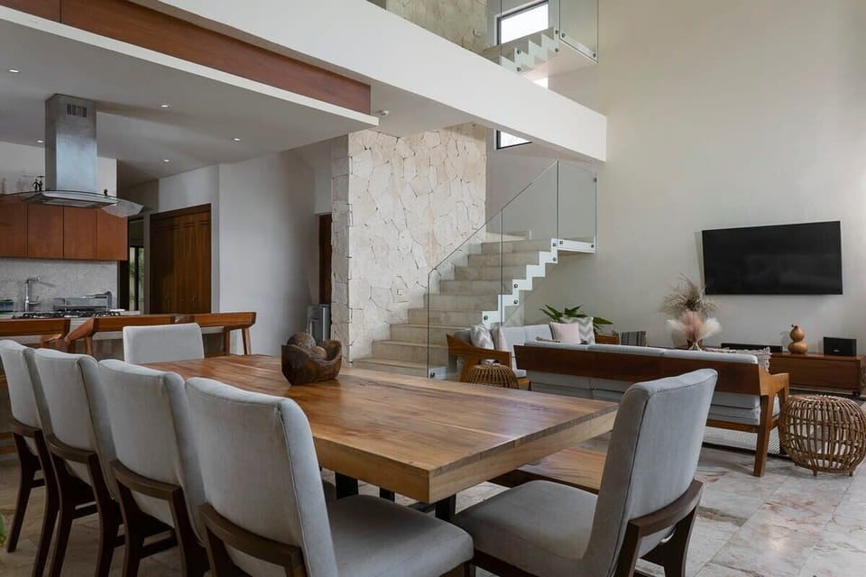 The ground floor is composed of the kitchen, dining area, and living room. Modern stairs lead to the second floor.
