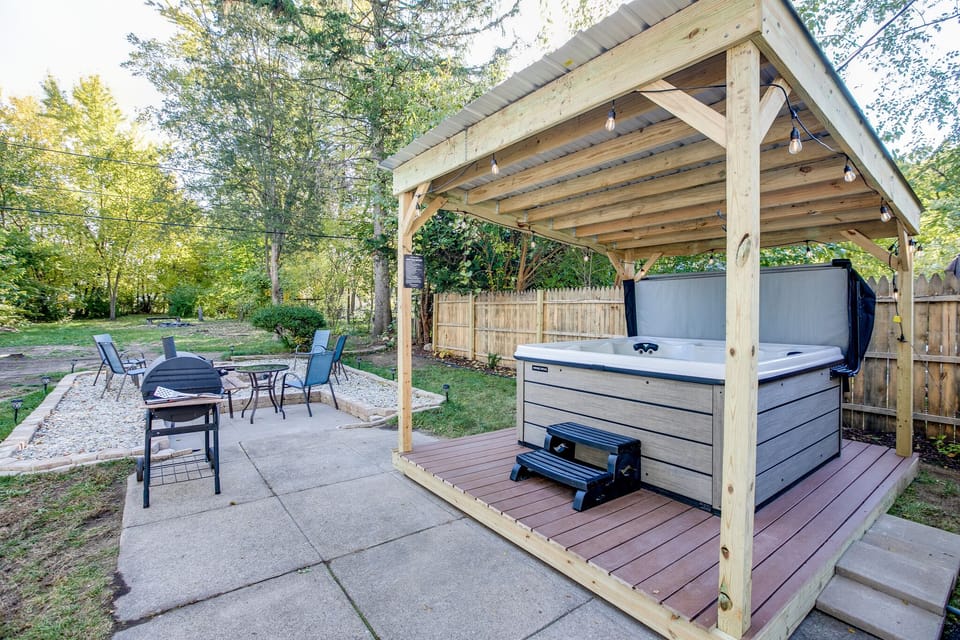 The backyard has a large grill, firepit, covered hot tub, and plenty of seating.