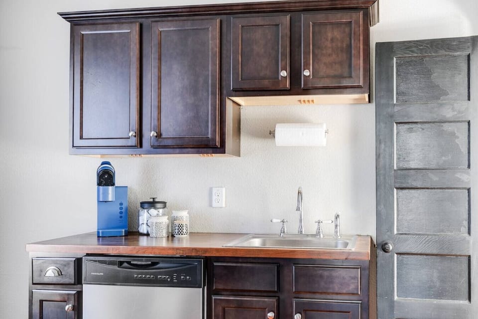 A fully equipped, well-lit space with an oven range, Keurig, dishwasher, and thoughtful touches like a paper towel dispenser. Perfect for whipping up meals or enjoying your morning coffee.