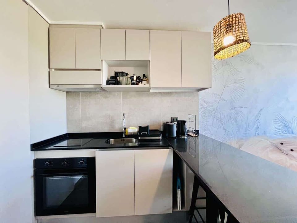 Sleek kitchen w/ modern cabinets, dark counters & stylish pendant lighting