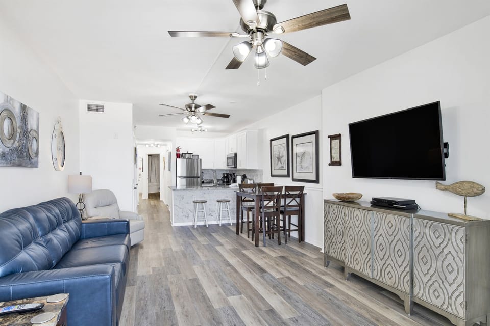 Living room with leather sleeper sofa, 2 leather rocking recliners, 55" wall mounted smart tv, 2 ceiling fans, 2 end tables with lamps, blackout curtains and beachside balcony access with an AMAZING view