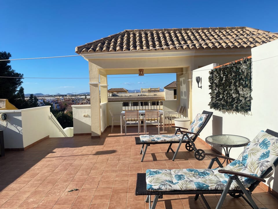 Rooftop terrace with three sun loungers and table and six chairs
