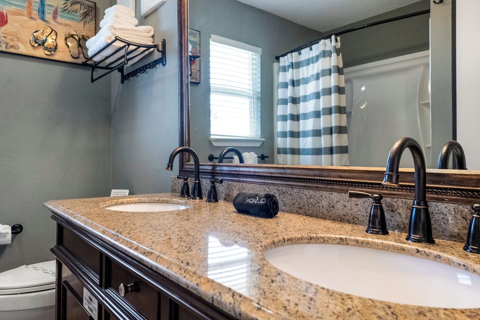 The bathroom has a shower-tub combo and double sinks.