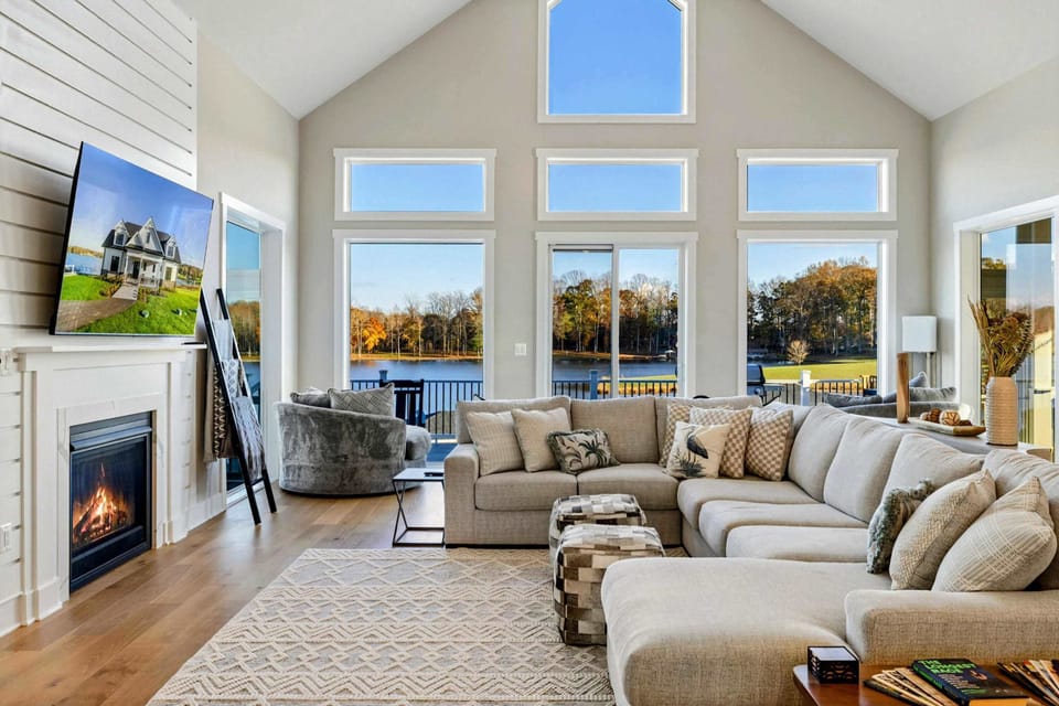 Bright and airy living room with a large sectional sofa, vaulted ceilings, and stunning lake views through expansive windows.