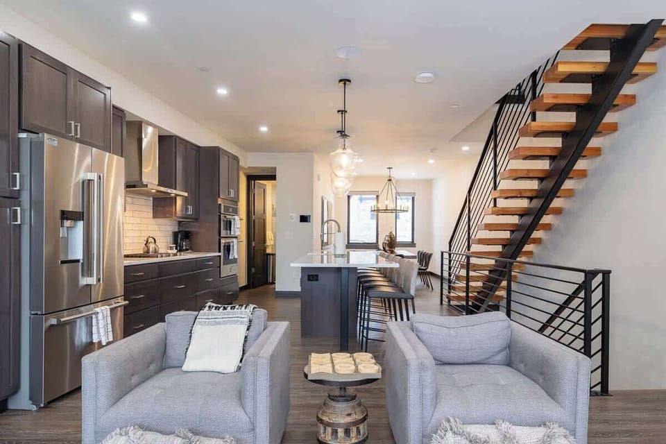 - Enjoy gourmet appliances, cozy seating, and stylish lighting in one open space
- Statement staircase adds modern flair to this warm and functional layout
- Perfect for meals, morning brews, and evening conversations