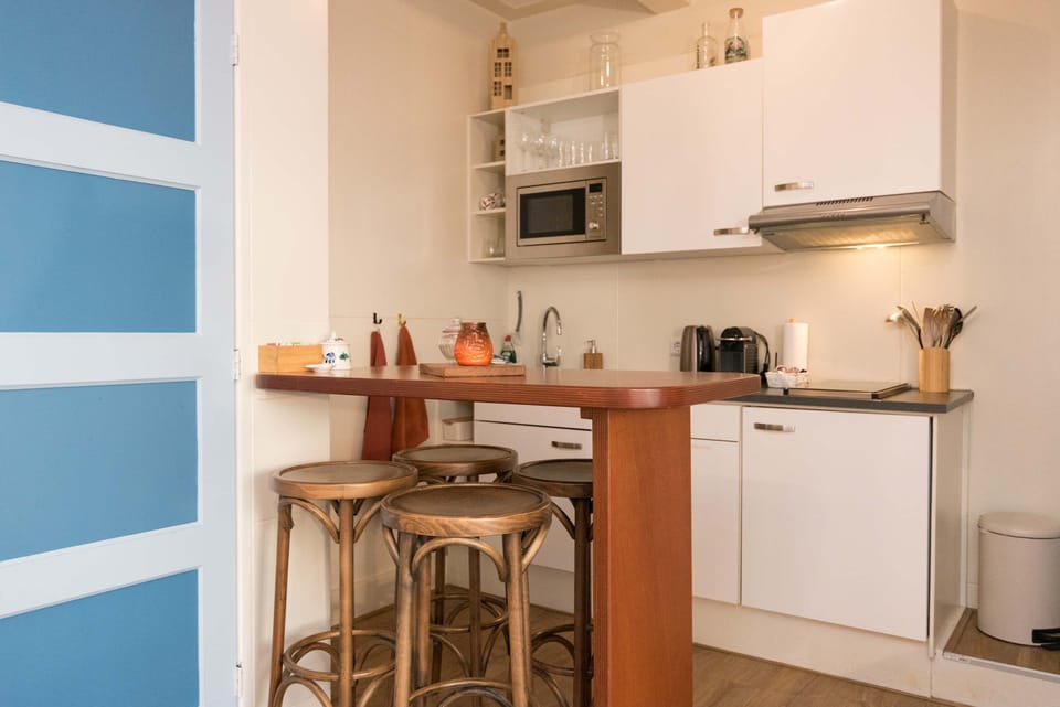 The warm dining area with wooden bar stools and a convenient kitchen layout makes dining comfortable and easy.