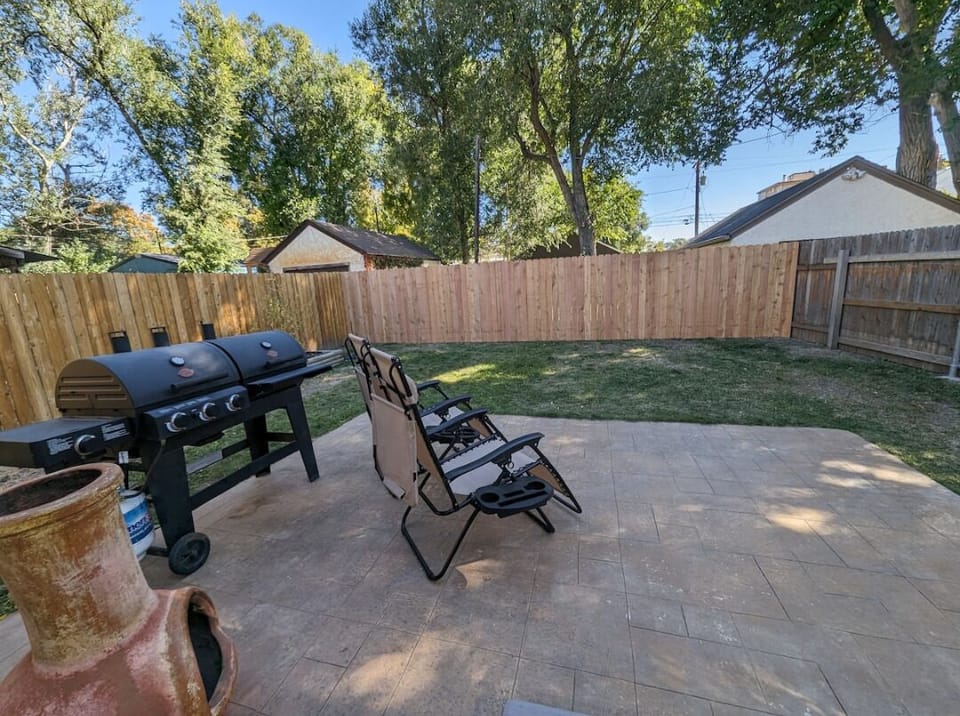 Private fenced in backyard w/ gravity chairs, deluxe grill, lush trees & table.