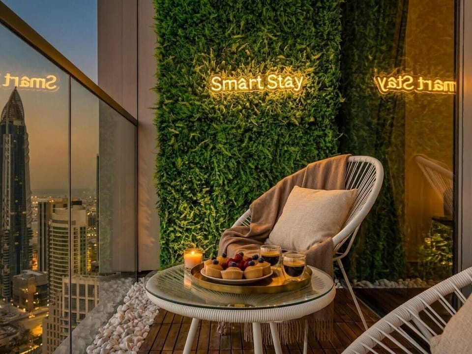 SmartStay Balcony with Green Wall Neon Sign Chair and Coffee Tray at Dusk