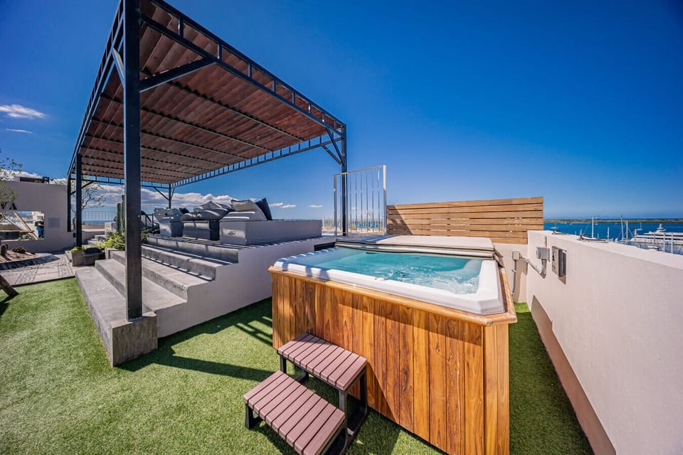 Rooftop con jacuzzi y vistas al mar, perfecto para relajarte al atardecer. Disfruta de cómodas áreas lounge bajo pérgola en un ambiente exclusivo y tranquilo.